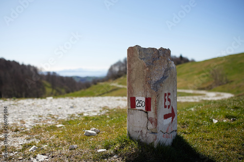 European path E5 with stone cippus and panorama of the mountains in the background