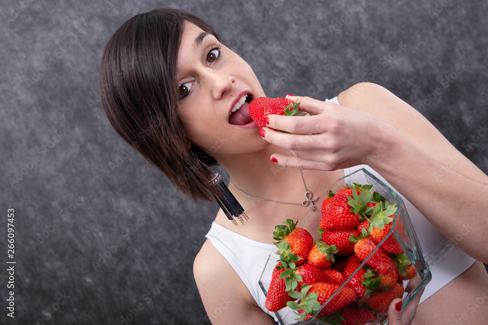 pretty young brunette woman eating strawberry