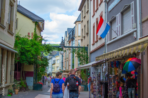 Narrow street in old town of Echternach, in Luxembourg, Europe. Typical houses with flags and tourists walking