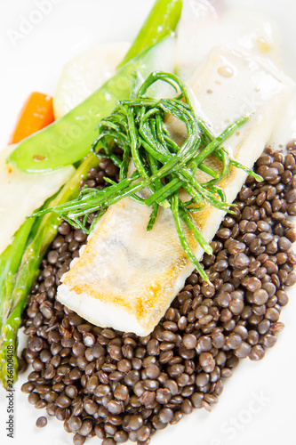 Grilled zander with black lentils, mixed green vegetables and lemon foam