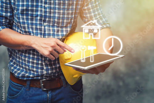Engineer holding helmet and using tablet checking for project Construction.