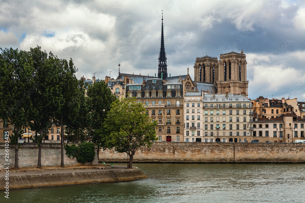 Spire and towers of Notre-Dame cathedral among parisian buildings.