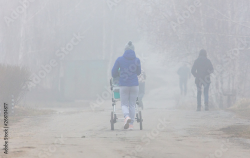 A girl with a stroller goes on the road to fog