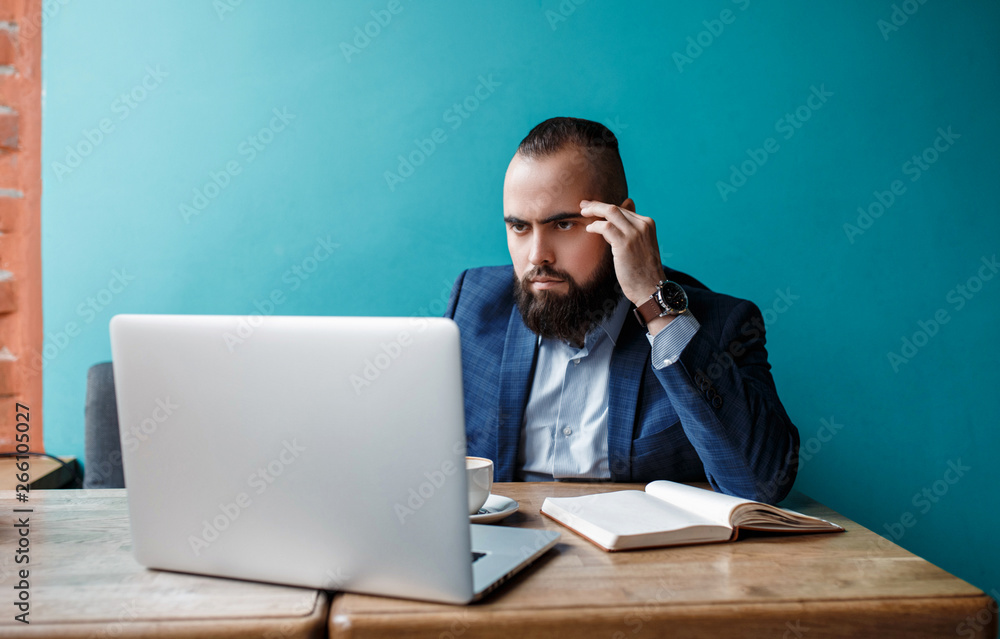 Businessman bearded man in a suit works behind the laptop sitting in a comfortable office coworking. Businessman bearded man in a suit works behind the laptop sitting in a comfortable office coworking.