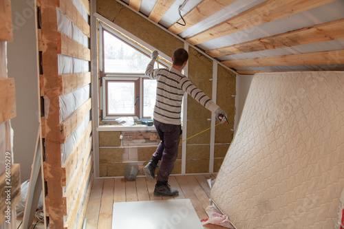 Worker installs drywall on the walls in the room