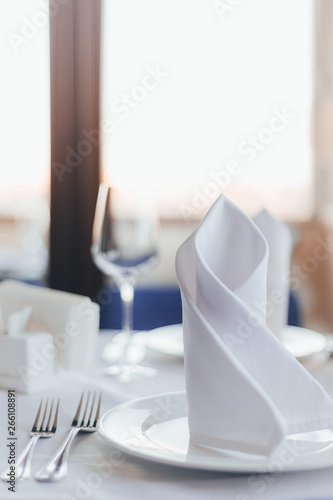 Close-up table in a restaurant. Glasses for wine, forks, spoons, napkins on a blurred light background