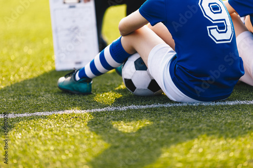 Young Soccer Player During Training Session. Children Sittion on Green Football Venue. Soccer Coaching Background. Sports Education photo