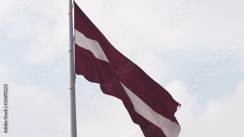Latvian flag fluttering in the wind high up in the sky during a Golden Hour sunset - Riga capital, Latvia - Dambis AB huge country national flag photo