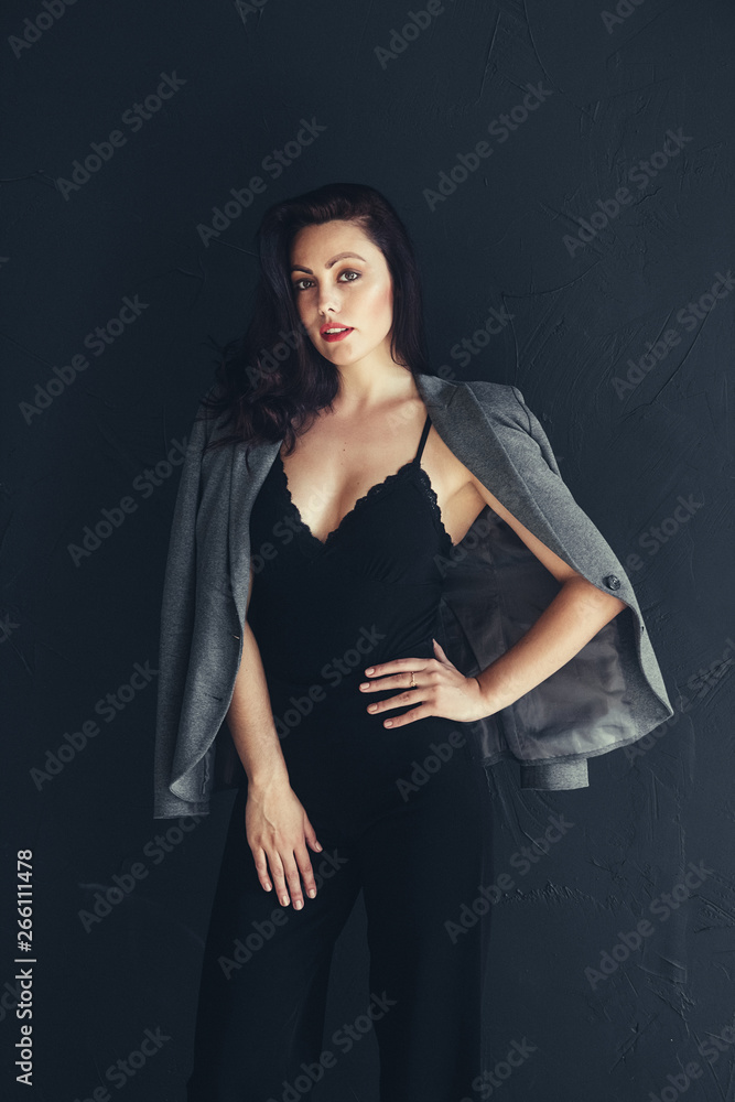 Beautiful young businesswoman studio shot on black background. Charming and confident serious brunette woman in casual dark grey jacket