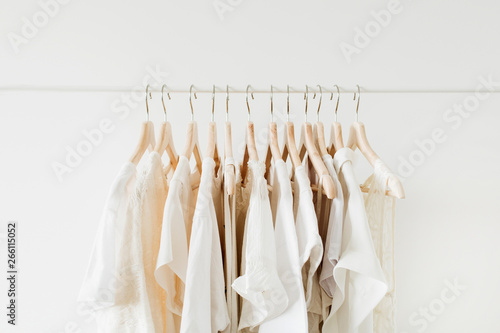 Minimal fashion clothes concept. White female blouses and t-shirts on hanger on white background.