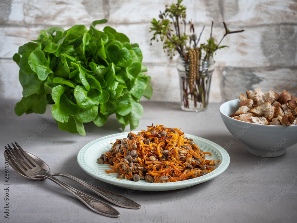 A light snack of lentils with roasted carrots and onions, crackers and salad on belos table. A light snack of lentils with roasted carrots and onions, crackers and salad on belos table.