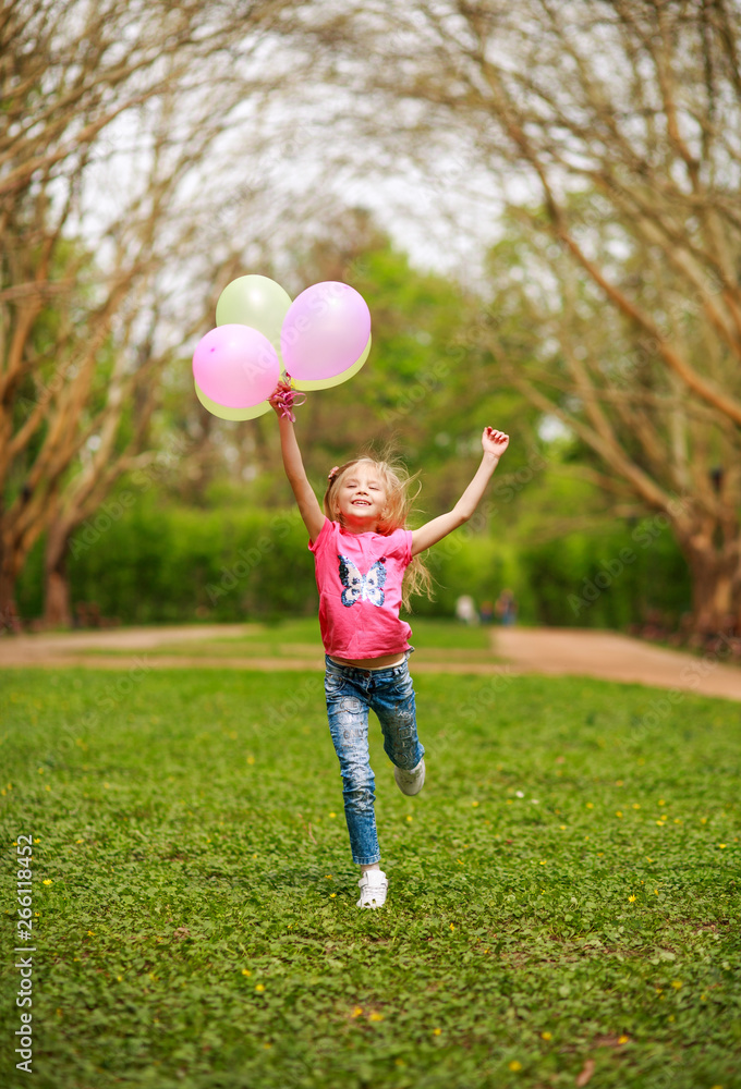 Happy girl with balloons jumping in city park celebrating summer lifestyle freshness of nature