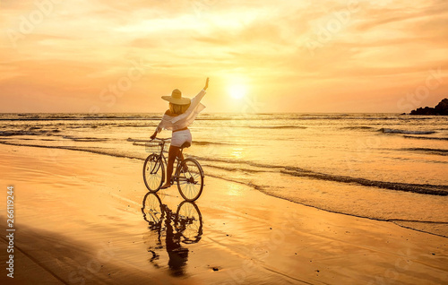 Happiness woman traveler with her bicycle rides on sea coastline