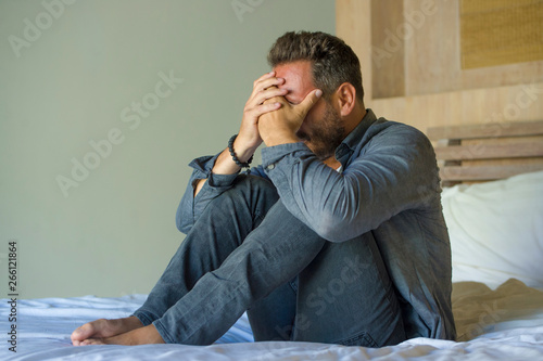 Tableau sur toile young attractive overwhelmed and depressed man sitting on bed worried and frustr