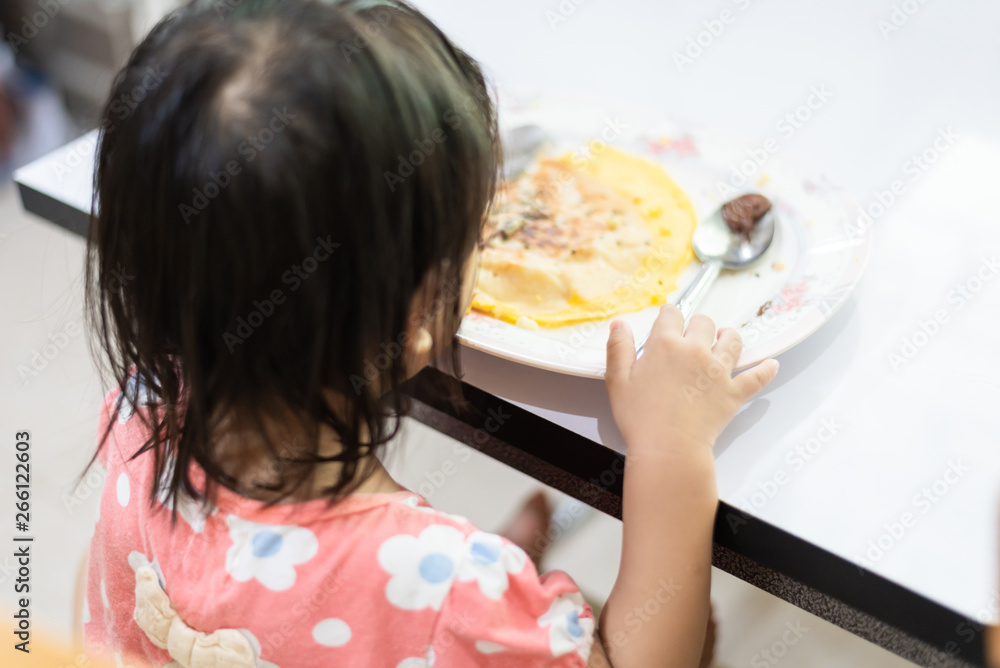 Asian little baby child eating and enjoy breakfast by herself Asian little baby child eating and enjoy breakfast by herself