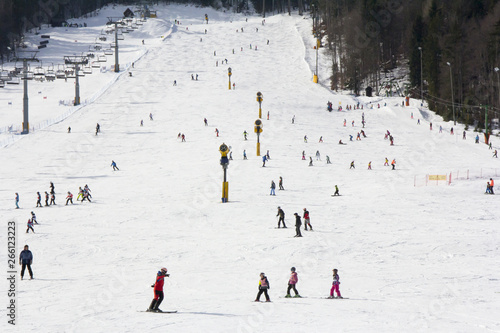 Lots of skiers and snowboarders on the slope at ski resort