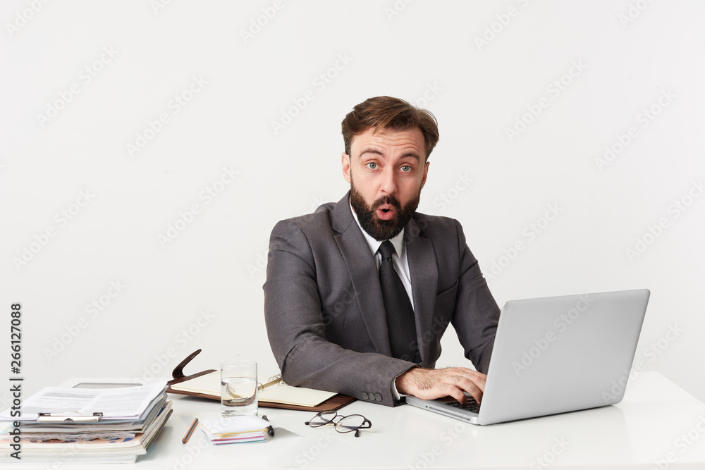 Portrait up of dressed in a suit respectable office worker sitting at desktop looking straight in confusion disbelief, mouth opened from shocking news. Portrait up of dressed in a suit respectable office worker sitting at desktop looking straight in confusion disbelief, mouth opened from shocking news.