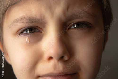Tears in the eyes of a child. A tear on the boy's cheek. © Maryna Osadcha