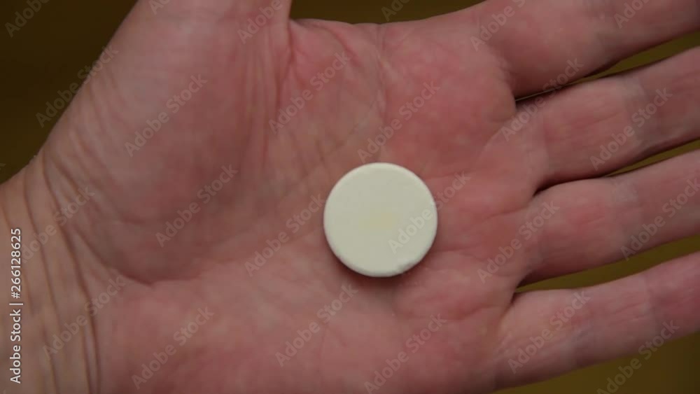 Man takes and shows pills vitamins or drugs tablets in hand from pill bottle, macro shot.White large round pills lie on the male palm which is squeezed into a fist. Man takes and shows pills vitamins or drugs tablets in hand from pill bottle, macro shot.White large round pills lie on the male palm which is squeezed into a fist.