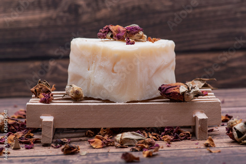 Wooden Soap Holder with a Heart shaped Goat milk Soap and dried roses on wooden background. photo