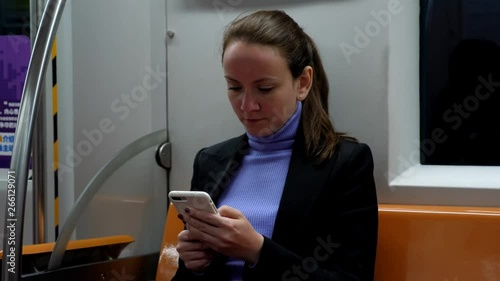 Woman texting in smartphone sitting at subway car