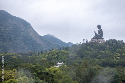 Giant buddha statue on mountain with green forest foreground and clouds sky background with copy space photo