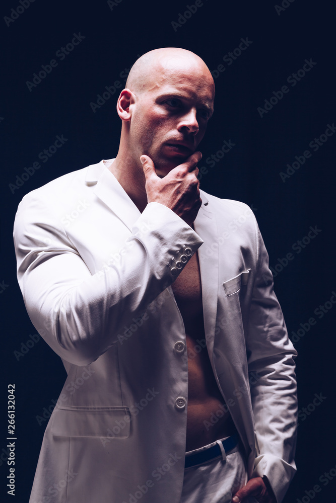 Elegant muscular attractive young man with white smart jacket open on naked torso. Fitness male bodybuilder posing.