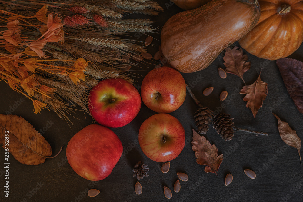 Ripe red apples with pumpkins in the background. Autumn background from yellow flowers, fruit and vegetables. Fall season, eco food and harvest concept. Selective focus. Toned image. Top view.