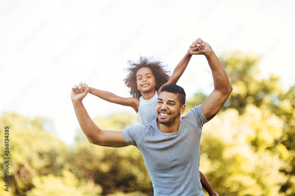 Portrait of young father carrying his daughter on his back Portrait of young father carrying his daughter on his back