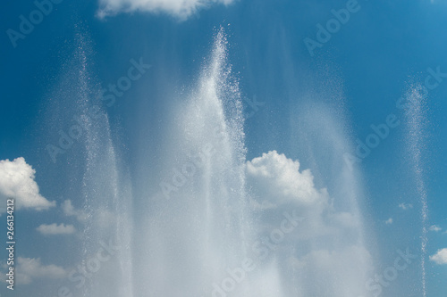 Fountain splashes against the blue sky and white clouds as a background