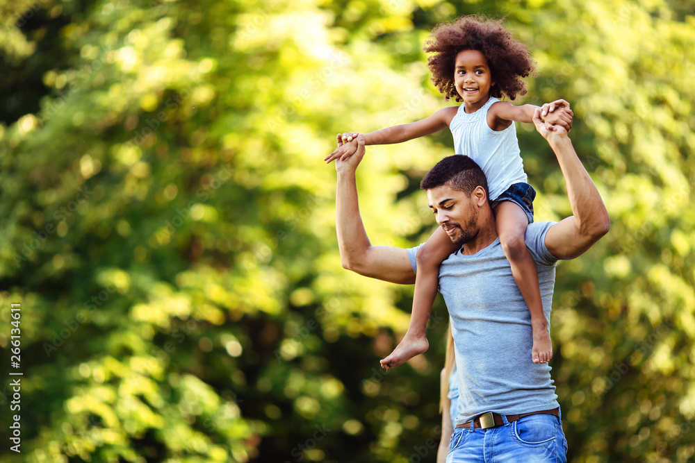 Fototapeta premium Portrait of young father carrying his daughter on his back
