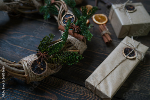 Christmas gift, rustic wreath with decorations, pine cones, fir branches on wooden brown background. Merry Christmas and Happy Holidays concept. Flat lay, top view, copy space. Toned image. Vintage.