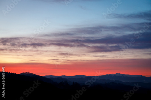 colorful sunset with glowing clouds and a tree a hill and valley silhouette in the austrian alps © woitzel
