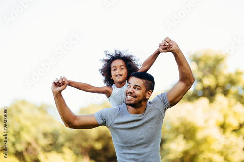 Portrait of young father carrying his daughter on his back