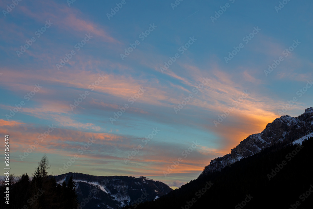 Obraz premium colorful sunset with glowing clouds above mountain tops in the austrian alps in winter