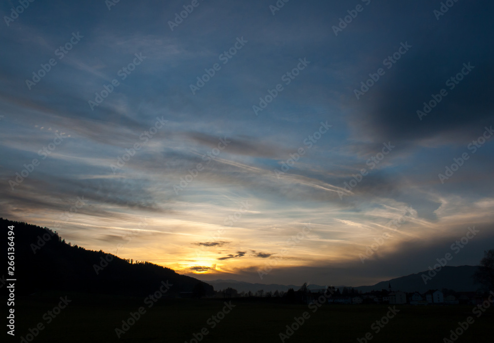 mystic sunset in the austrian alps with mighty clouds in front of the sun
