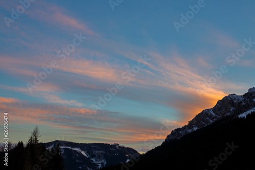 colorful sunset with glowing clouds above mountain tops in the austrian alps in winter