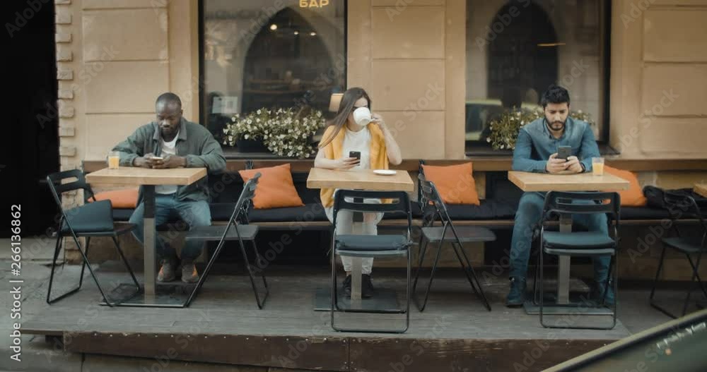 Front view of outdoors cafe with loneliness people using gadgets for chatting Front view of outdoors cafe with loneliness people using gadgets for chatting