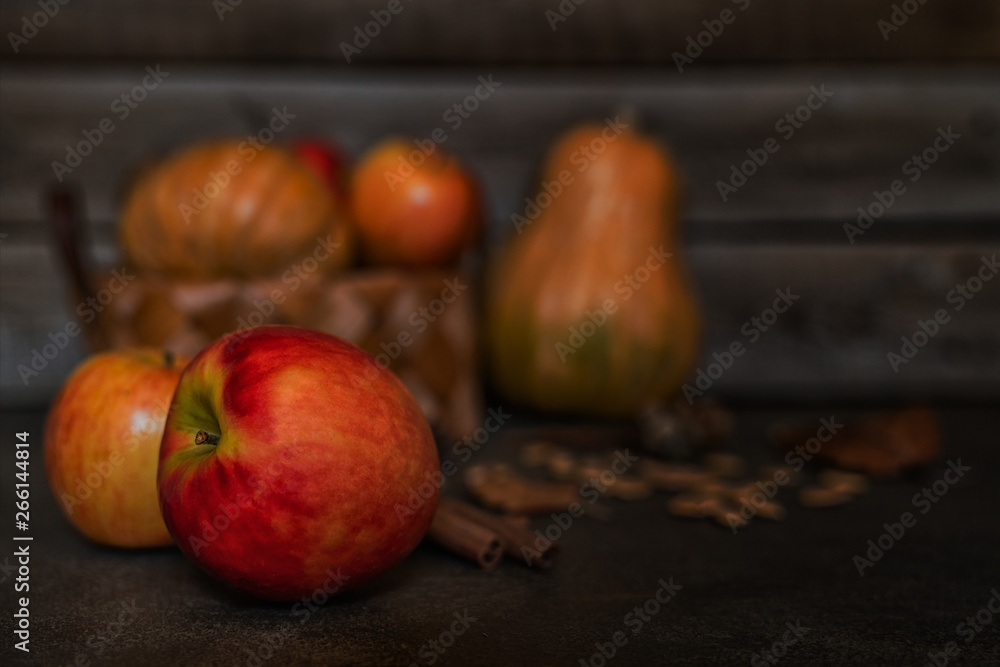 Ripe red apples with pumpkins in the basket in the background. Autumn background from yellow flowers, fruit and vegetables. Fall season, eco food and harvest concept. Selective focus. Toned image. Ripe red apples with pumpkins in the basket in the background. Autumn background from yellow flowers, fruit and vegetables. Fall season, eco food and harvest concept. Selective focus. Toned image.