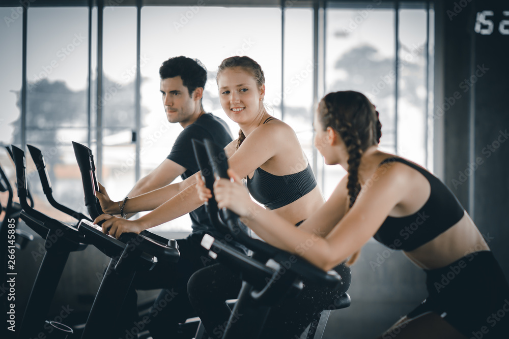 Group of people biking in the gym, exercising legs doing cardio workout cycling bikes. Couple in a spinning class wearing sportswear. Fitness, Healthy, Sport, Lifestyle concept.v Group of people biking in the gym, exercising legs doing cardio workout cycling bikes. Couple in a spinning class wearing sportswear. Fitness, Healthy, Sport, Lifestyle concept.v