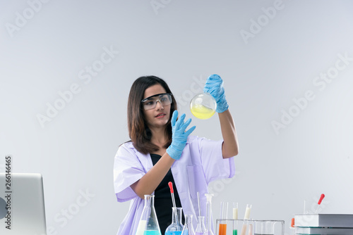 Cheerful  chemist woman in lap, or graduate student in lab coat ane protetive wear work,check and test chemistry. photo