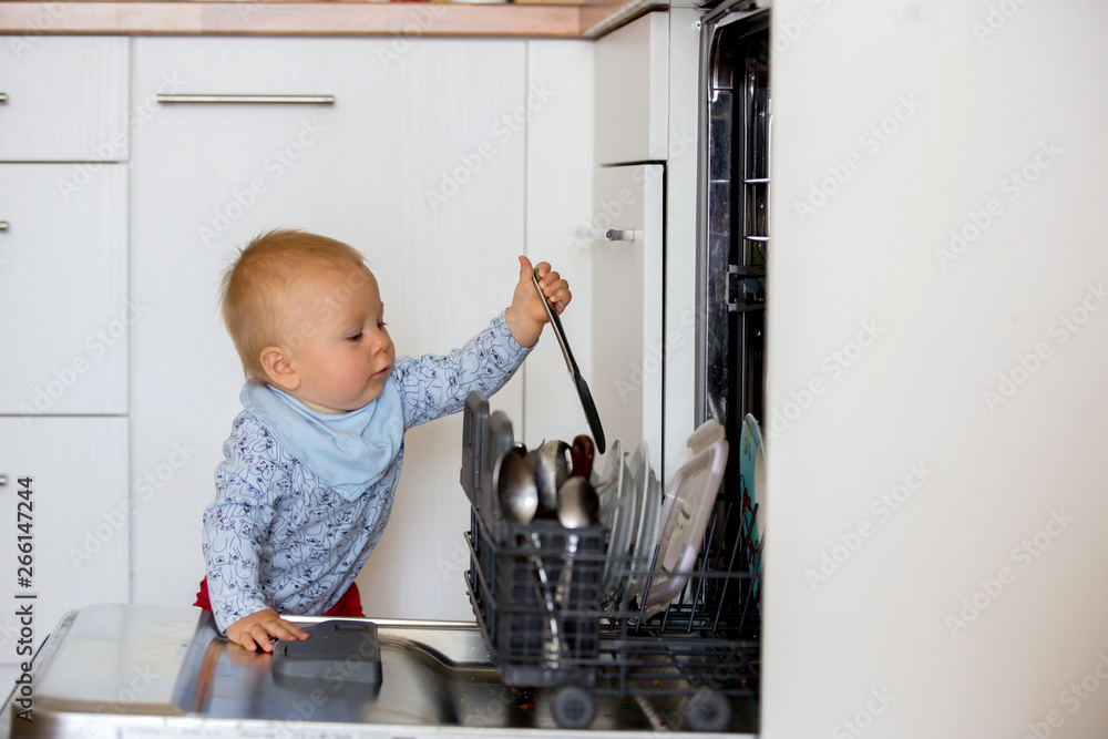 Toddler child, boy, helping mom, putting dirty dishes in dishwasher at home, . Toddler child, boy, helping mom, putting dirty dishes in dishwasher at home, .