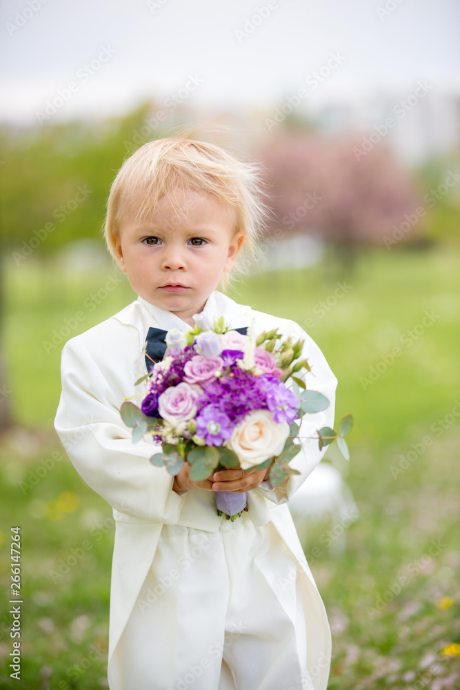 Beautiful toddler boy, dressed in white tuxedo, holding gorgeous flower bouquet for mothers day Beautiful toddler boy, dressed in white tuxedo, holding gorgeous flower bouquet for mothers day
