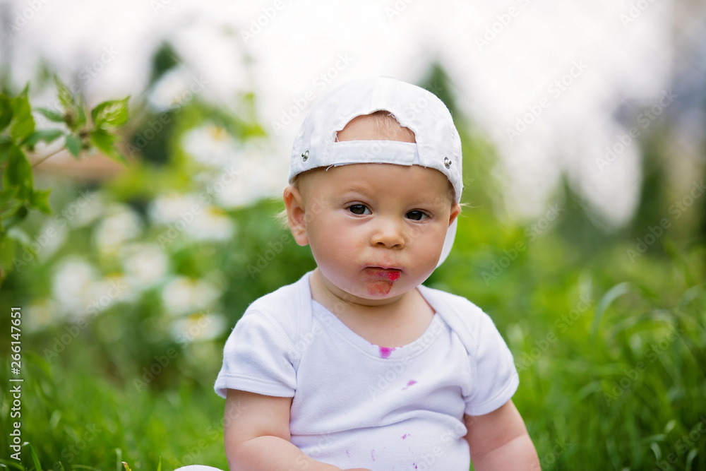 Sweet little child, baby boy, eating cherries in garden, enjoying tasty fruit Sweet little child, baby boy, eating cherries in garden, enjoying tasty fruit
