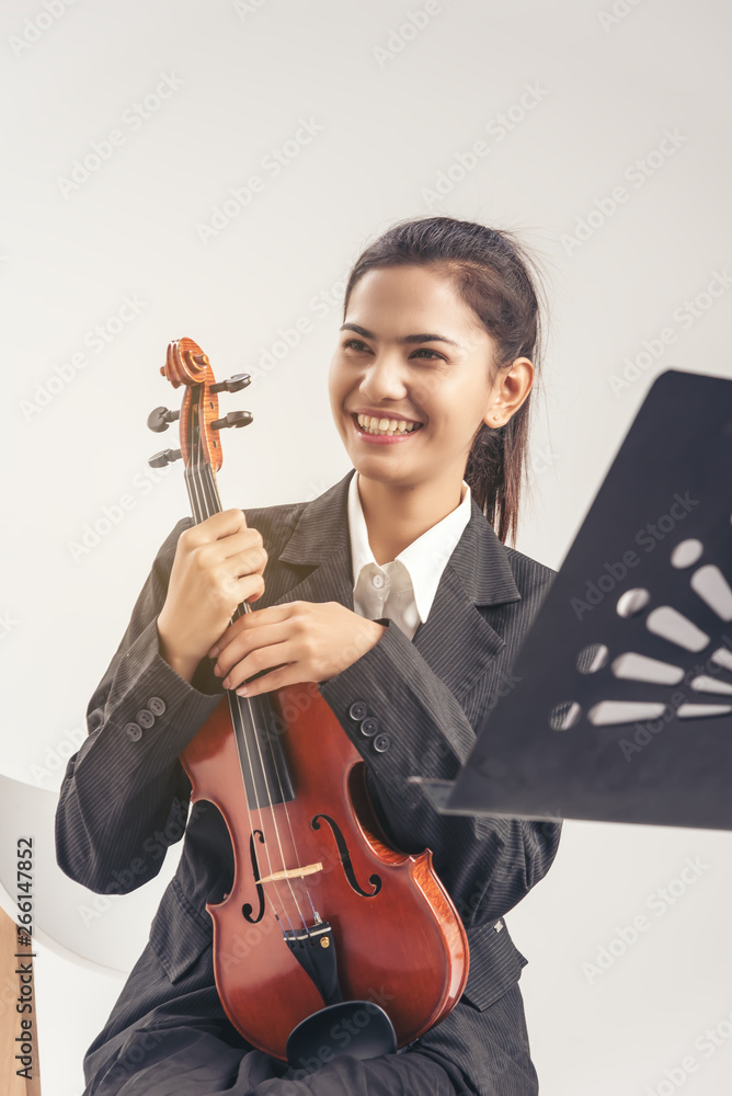 In violin practice class,Beautiful asia woman sit and hold wooden violin.learn and practice playing violin together to prepare for the concert.smile and happy.education concept In violin practice class,Beautiful asia woman sit and hold wooden violin.learn and practice playing violin together to prepare for the concert.smile and happy.education concept