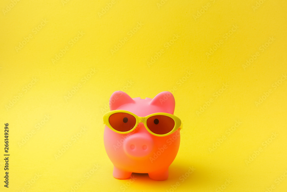 Pink piggy bank with sunglasses on yellow background. with free space Pink piggy bank with sunglasses on yellow background. with free space
