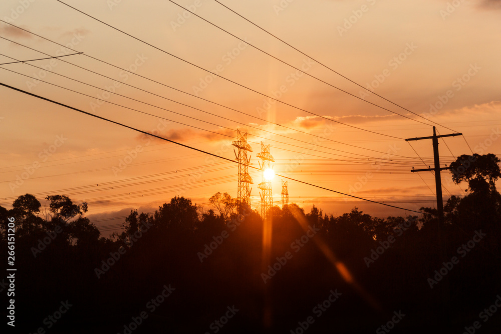 Afternoon sunshine beaming through electricity pylons.