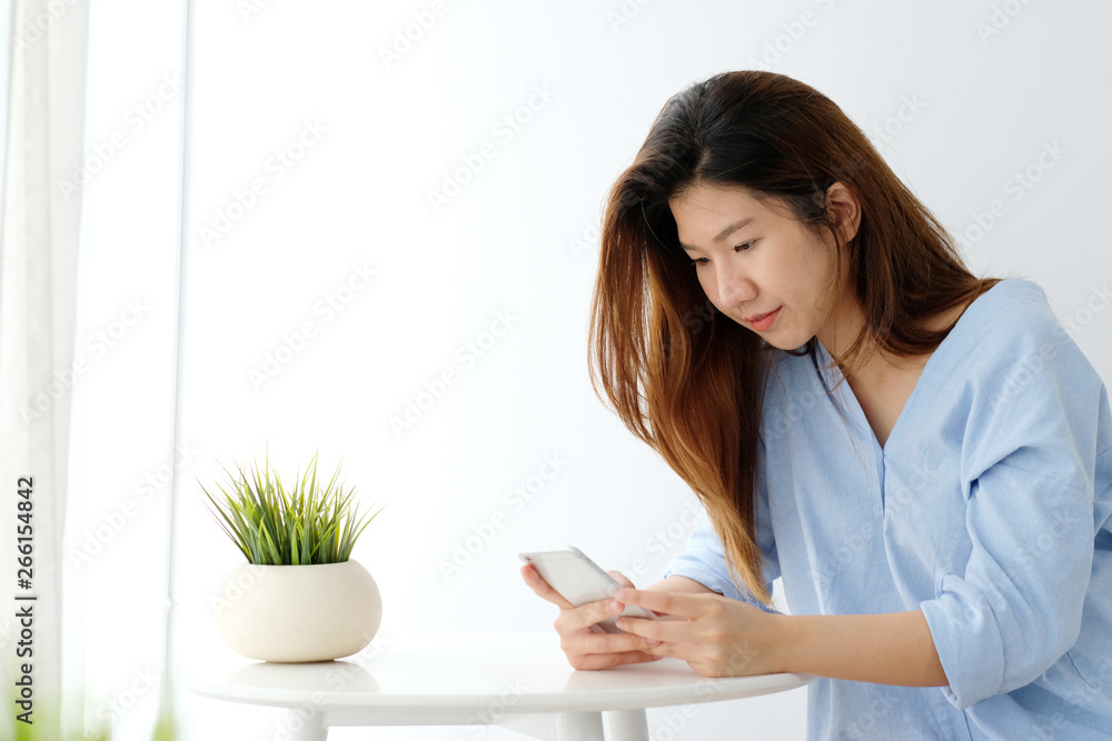 Young asian woman using smart phone with smiling, happy and relax emotion in white room background, people on phone, lifestyle Young asian woman using smart phone with smiling, happy and relax emotion in white room background, people on phone, lifestyle