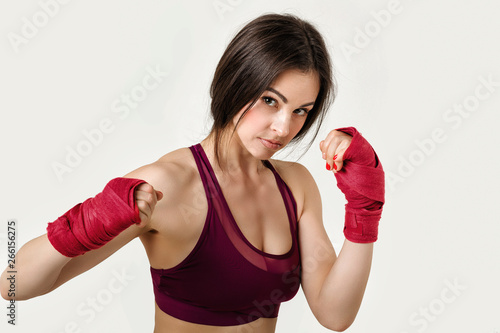 beautiful woman boxer with red strap on wrist. Fitness girl preparing for boxing training on gray background © producer