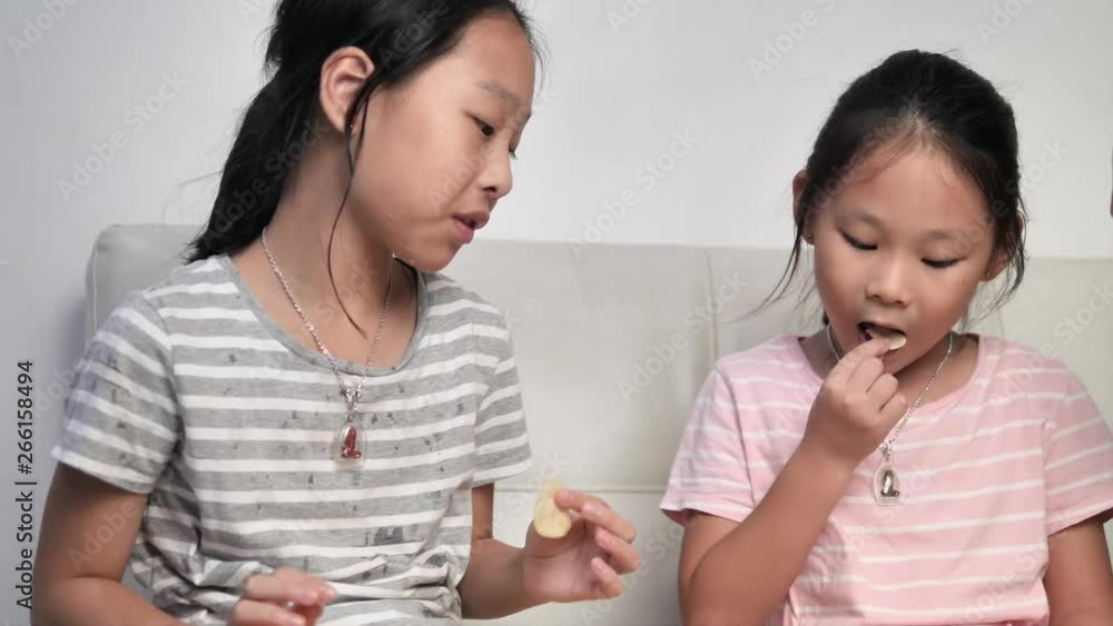 Happy Asian children eating potato chips together at home. Happy Asian children eating potato chips together at home.